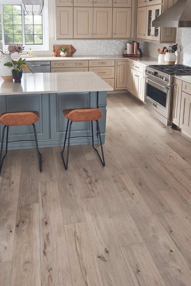wood-look laminate flooring in kitchen with blue island and leather bar stools